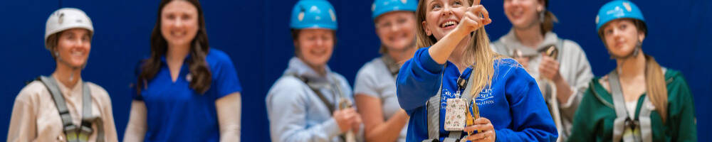Students in helmets and harnesses holding climbing ropes